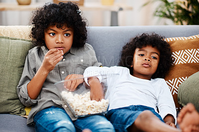 Buy stock photo Cropped shot of two adorable little boys eating popcorn and watching movies together at home
