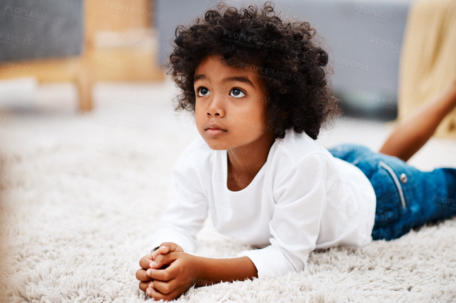 Buy stock photo Cropped shot of an adorable little boy lying down on a carpet and watching tv at home