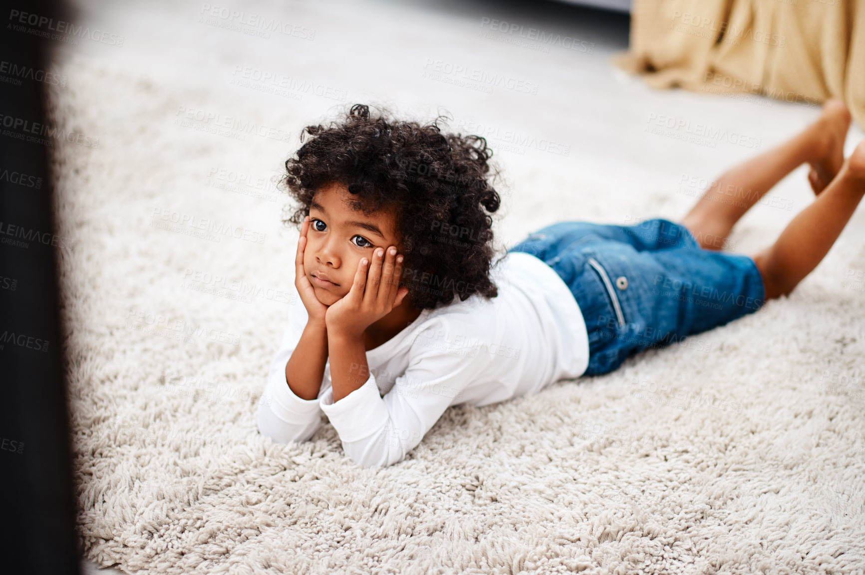Buy stock photo Cropped shot of an adorable little boy lying down on a carpet and watching tv at home