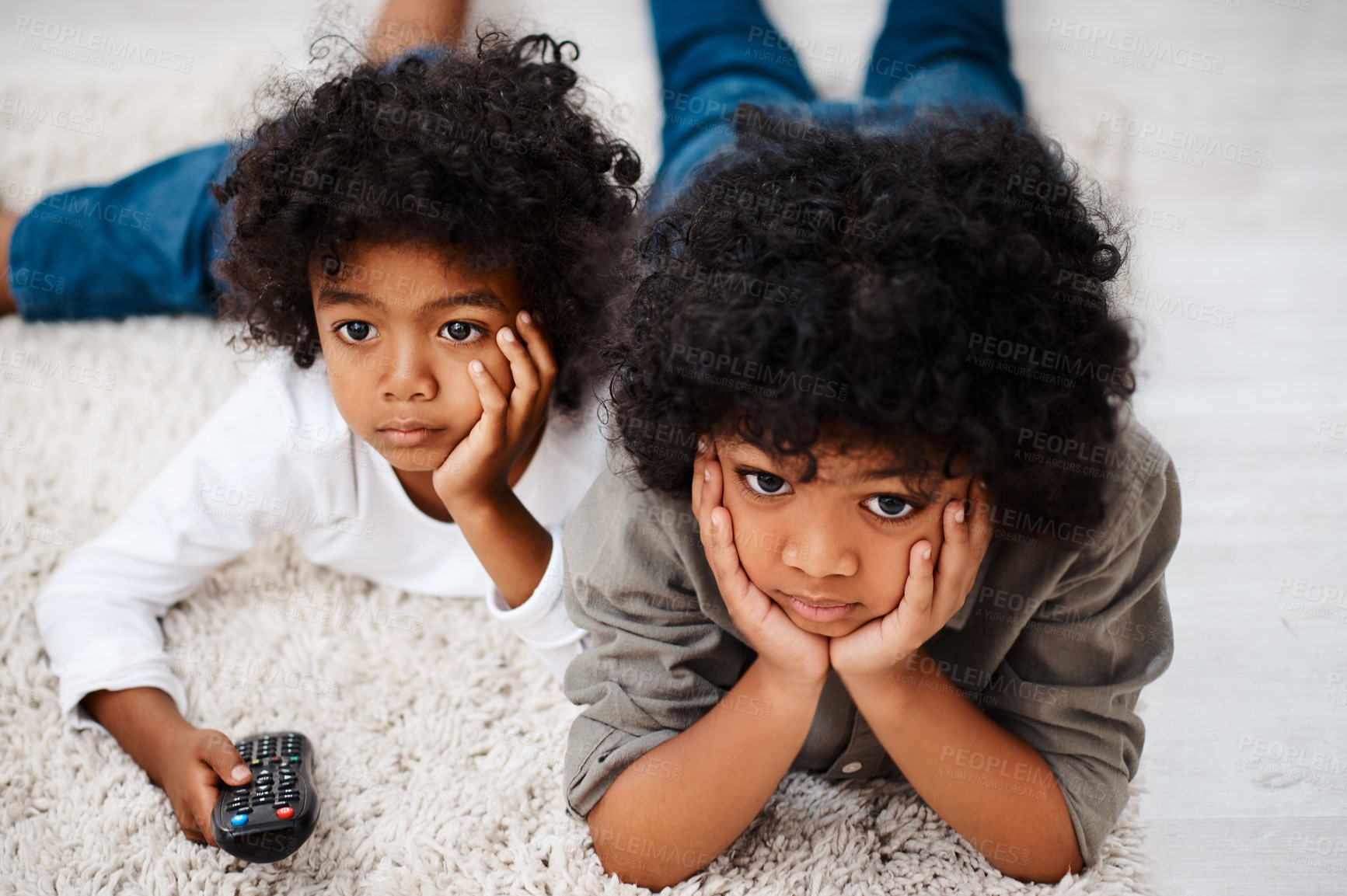 Buy stock photo Cropped shot of two adorable little boys lying down on a carpet and watching tv together at home