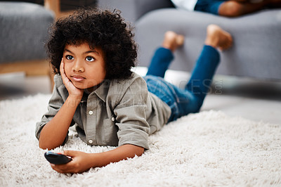 Buy stock photo Full length shot of an adorable little boy lying down on a carpet and watching tv at home