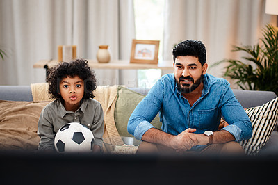 Buy stock photo Cropped shot of an adorable little boy watching a football game with his father on tv at home