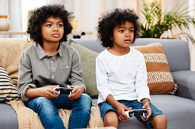 Buy stock photo Cropped shot of two adorable little boys sitting on a sofa and playing video games together at home