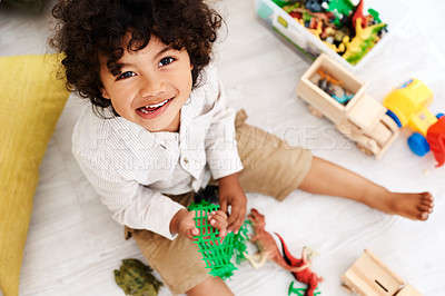 Buy stock photo Portrait of an adorable little boy sitting on the floor and playing with his toys at home