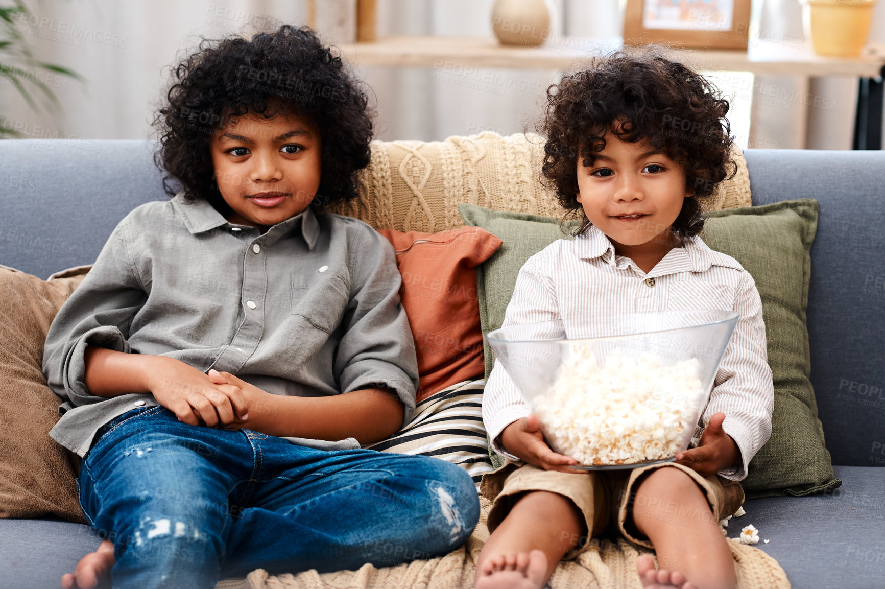 Buy stock photo Cropped shot of two adorable little boys eating popcorn and watching movies together at home