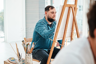 Buy stock photo Cropped shot of a handsome young artist sitting and painting during an art class in the studio
