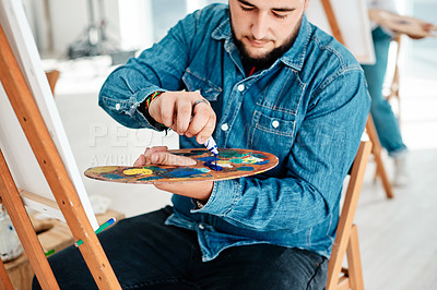 Buy stock photo Cropped shot of a handsome young artist squeezing paint onto a palette during an art class in the studio