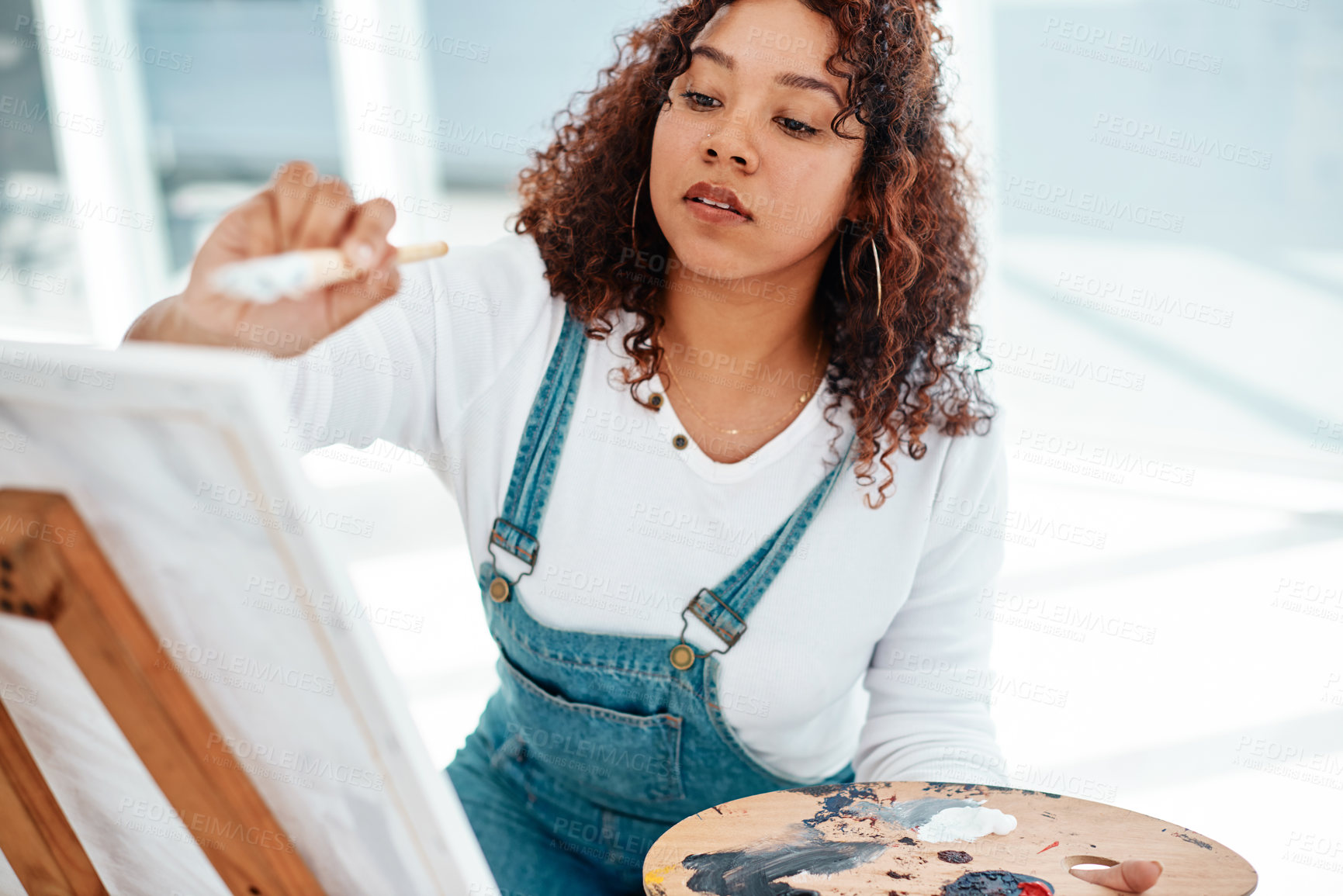 Buy stock photo Cropped shot of an attractive young artist sitting alone and painting during an art class in the studio