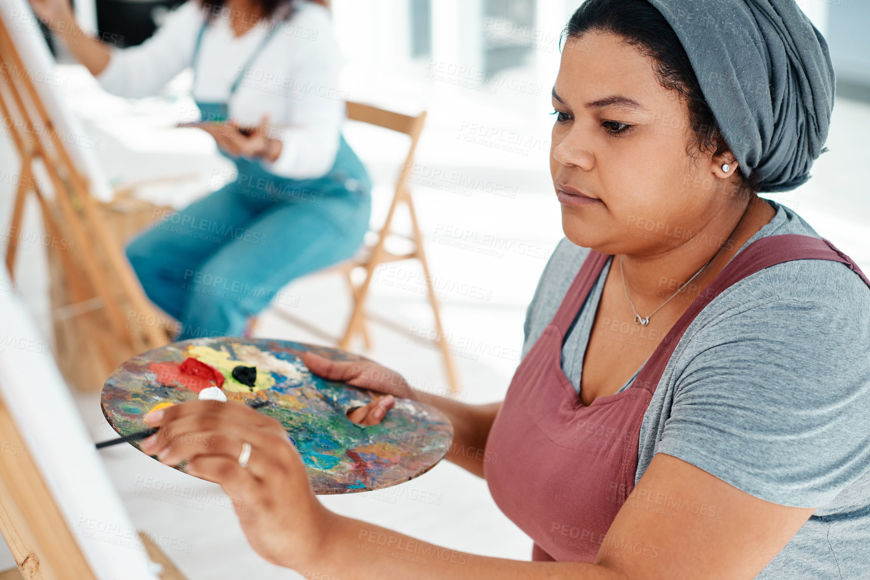 Buy stock photo Cropped shot of an attractive young woman sitting with her friends and painting during an art class in the studio