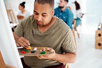 Buy stock photo Cropped shot of a handsome young artist sitting and painting during an art class in the studio
