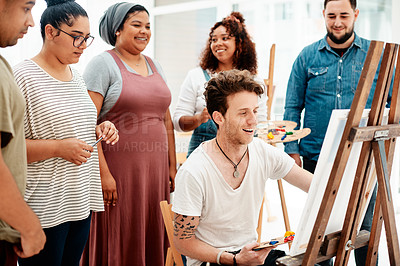 Buy stock photo Cropped shot of a handsome young man sitting and explaining his artwork to his friends during an art class