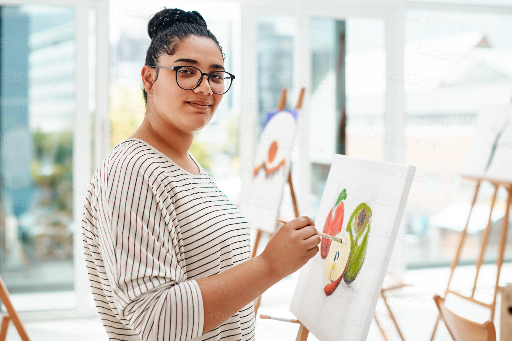 Buy stock photo Cropped portrait of an attractive young artist standing alone and painting during an art class in the studio