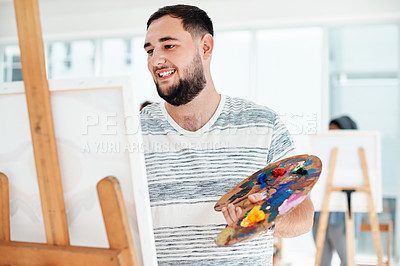 Buy stock photo Cropped shot of a handsome young artist standing alone and painting during an art class in the studio