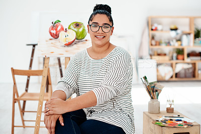 Buy stock photo Cropped portrait of an attractive young artist sitting next to her painting during an art class in the studio