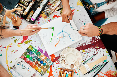 Buy stock photo Hands, painting and paintbrush with mess on table, creative and colourful or talent expression in art class. People, together and canvas for learning and education with artists, friends and splatter
