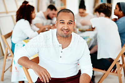 Buy stock photo Cropped portrait of a handsome young man sitting with his friends during an art class in the studio