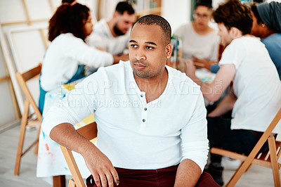 Buy stock photo Cropped shot of a handsome young artist sitting and looking contemplative during an art class in the studio