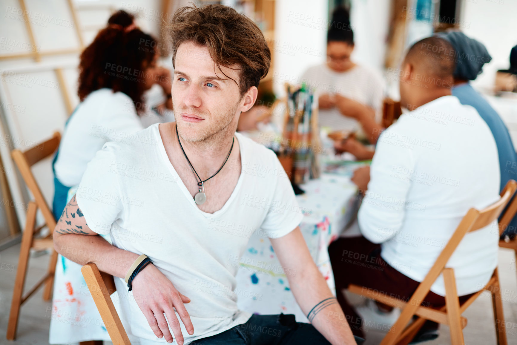 Buy stock photo Cropped shot of a handsome young artist sitting and looking contemplative during an art class in the studio