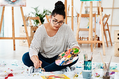Buy stock photo Full length shot of an attractive young artist sitting alone and painting during an art class in the studio