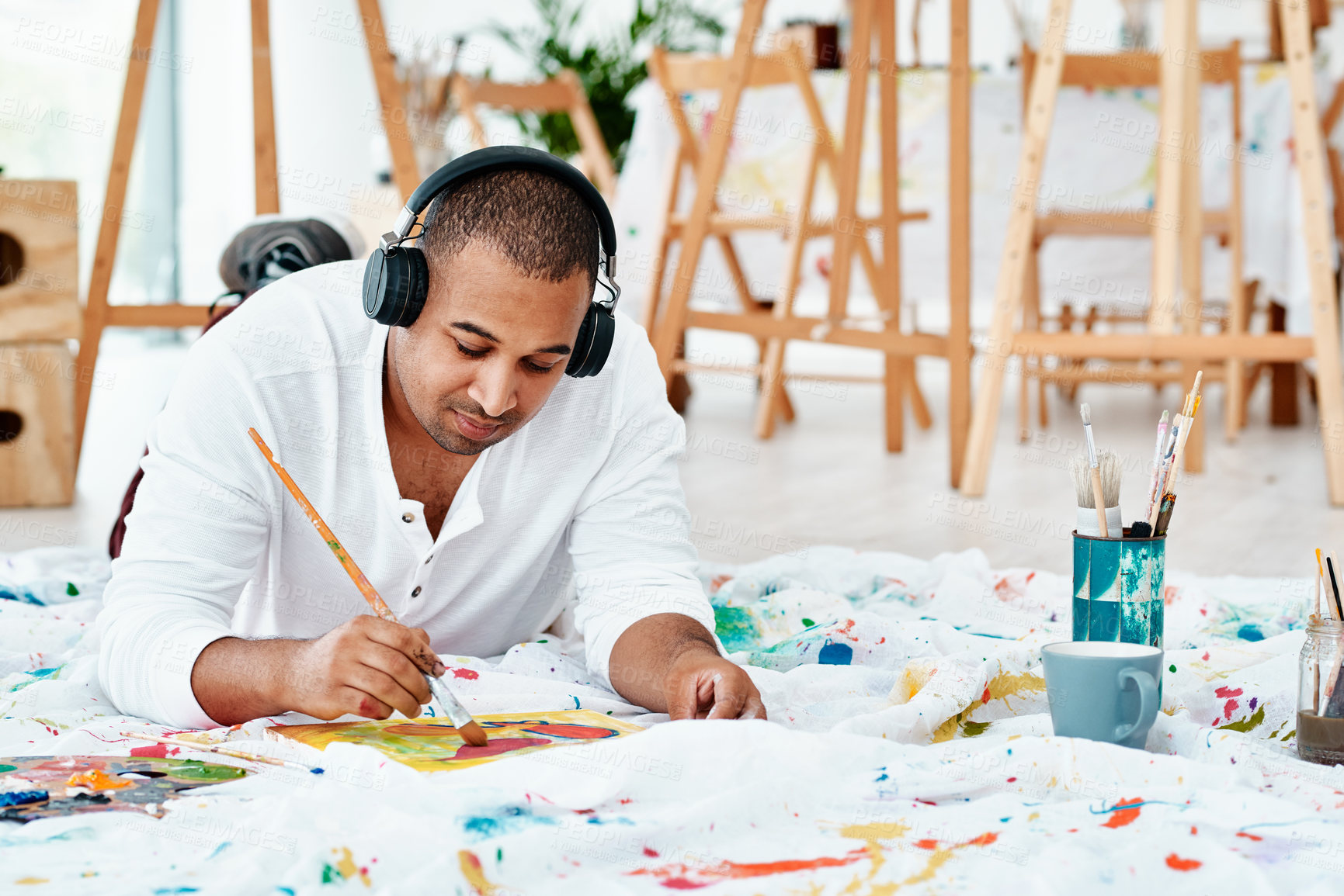 Buy stock photo Headphones, painter and man listening to music for art school, drawing or relax in studio. Audio, creative artist and painting on canvas with brush, color or palette for talent in university workshop