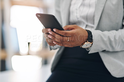 Buy stock photo Cropped shot of an unrecognizable businesswoman using a cellphone while working inside her office