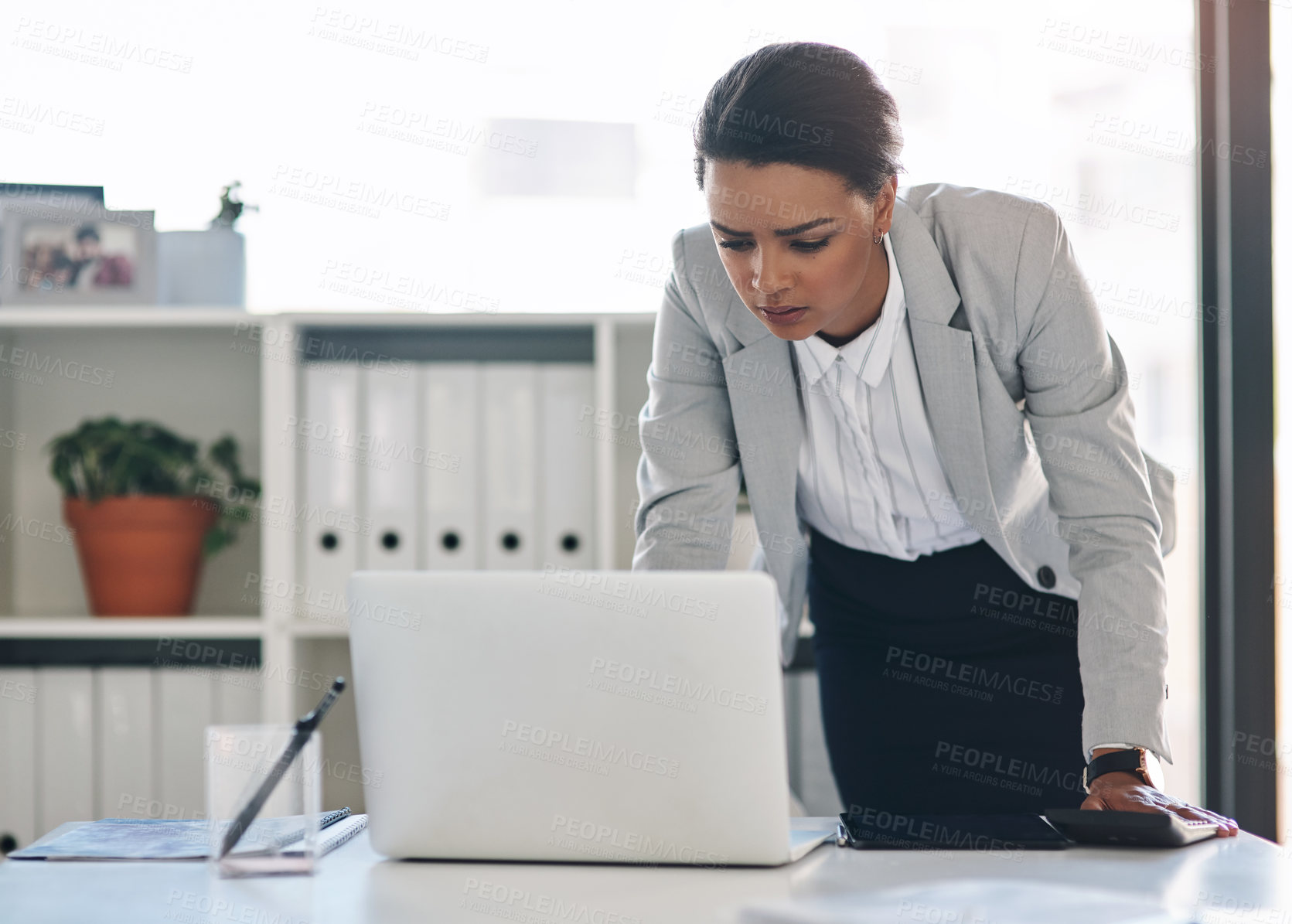 Buy stock photo Cropped shot of an attractive young businesswoman working on a laptop inside her office