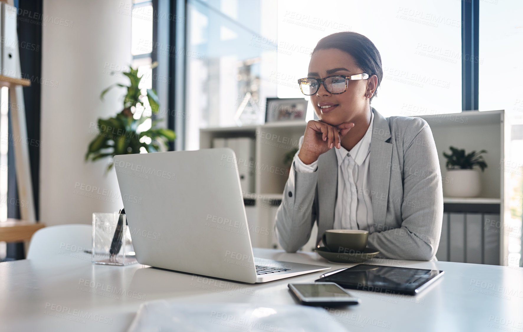 Buy stock photo Cropped shot of an attractive young businesswoman working on a laptop inside her office