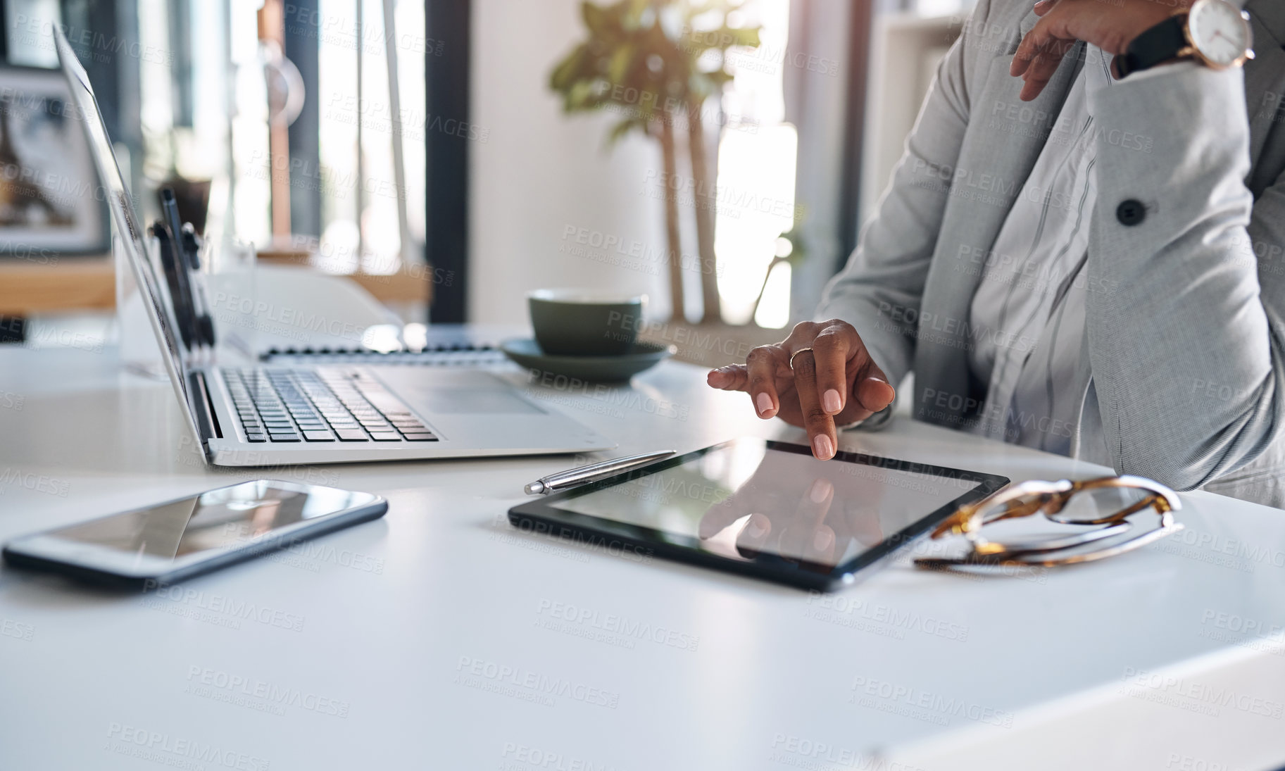 Buy stock photo Cropped shot of an unrecognizable businesswoman using a digital tablet while working inside her office