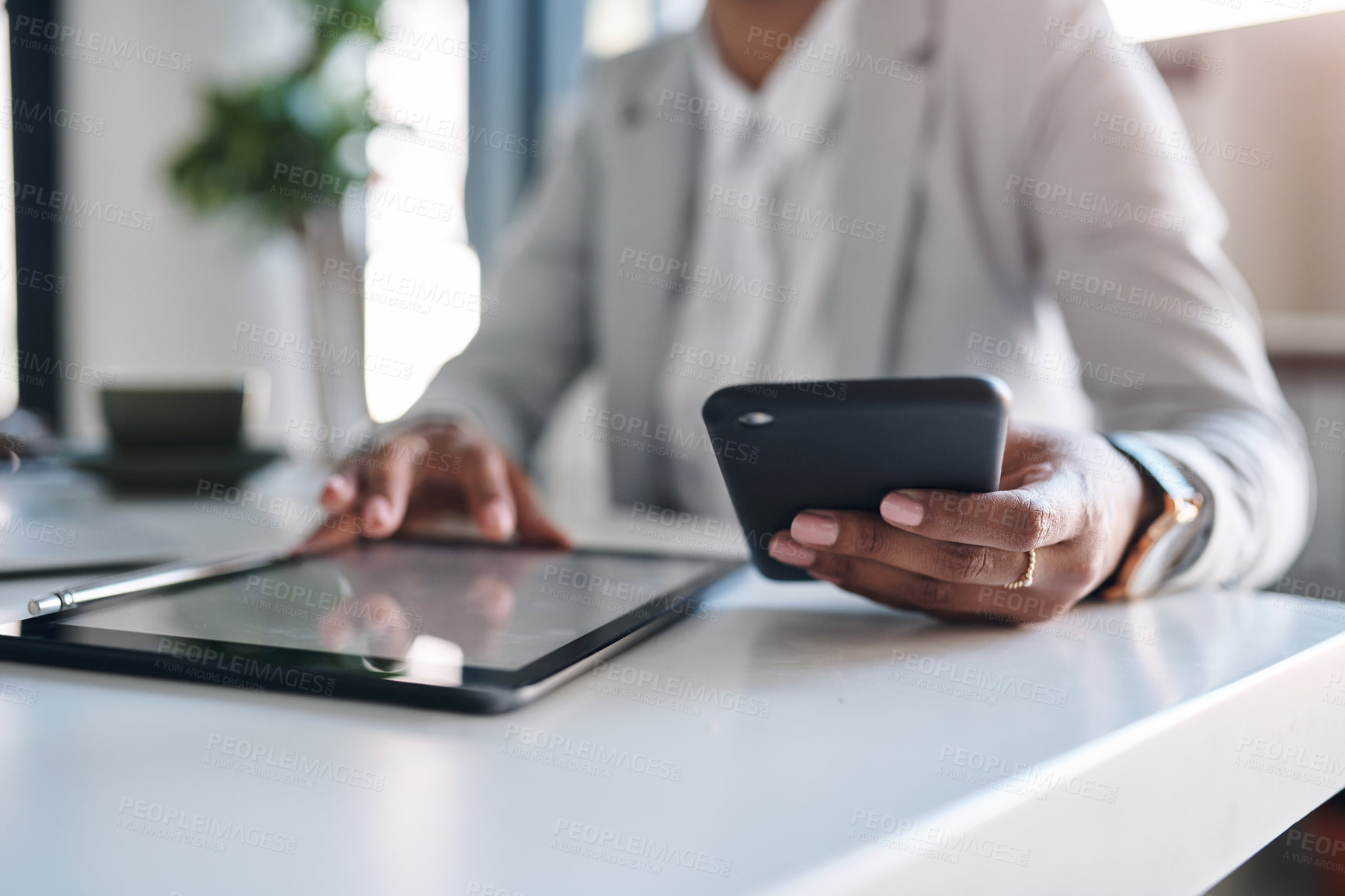 Buy stock photo Cropped shot of an unrecognizable businesswoman using a digital tablet and her cellphone while working inside her office