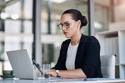 Buy stock photo Cropped shot of an attractive young businesswoman working on a laptop inside her office