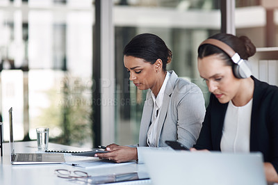 Buy stock photo Cropped shot of an attractive young businesswoman listening to music while working next to a colleague inside an office