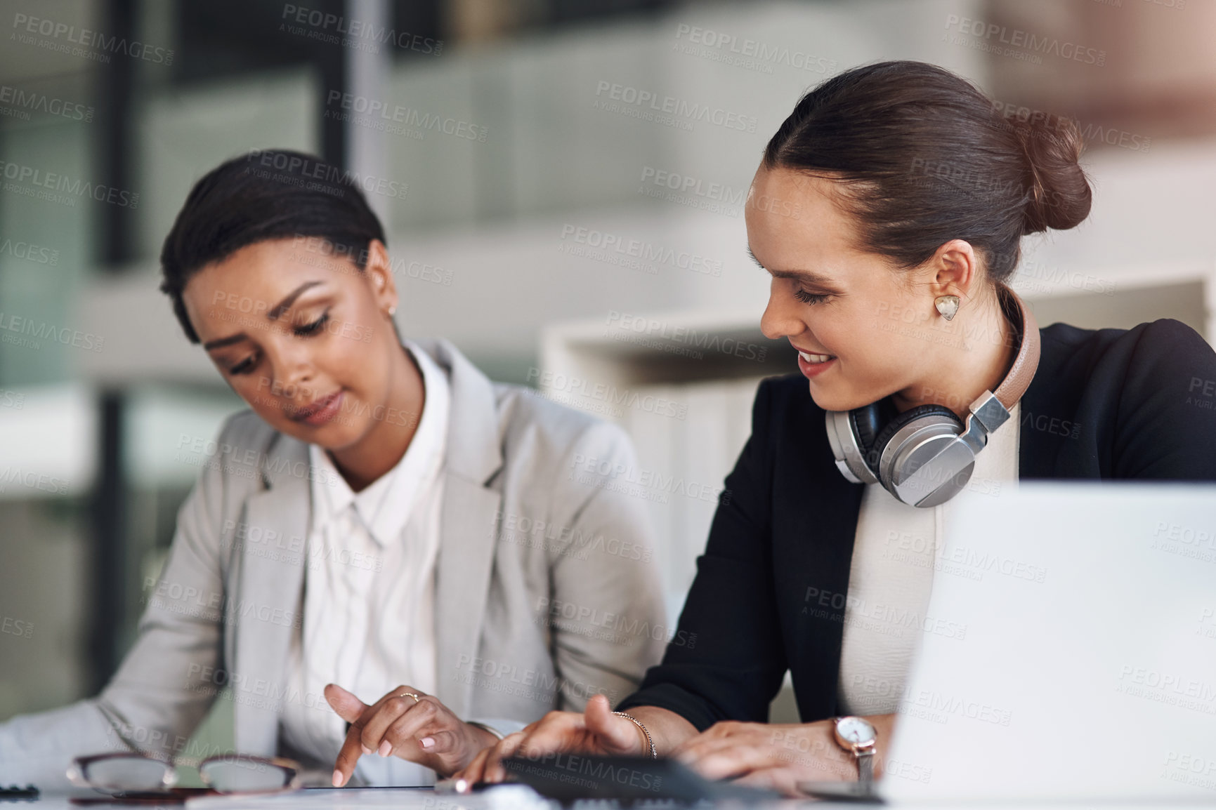 Buy stock photo Cropped shot of two attractive young businesswomen working together inside a modern office