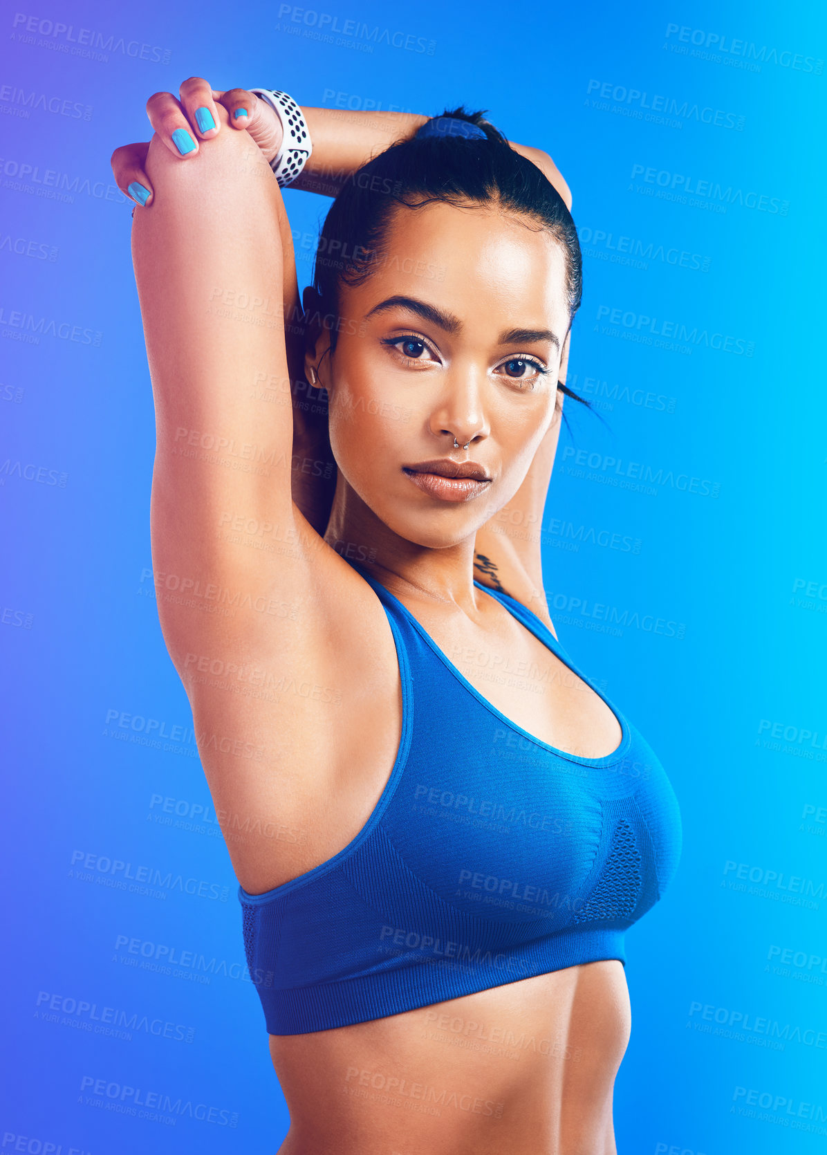 Buy stock photo Studio portrait of an attractive young sportswoman stretching her arms against a blue background