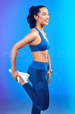 Buy stock photo Studio shot of an attractive young sportswoman stretching her leg against a blue background