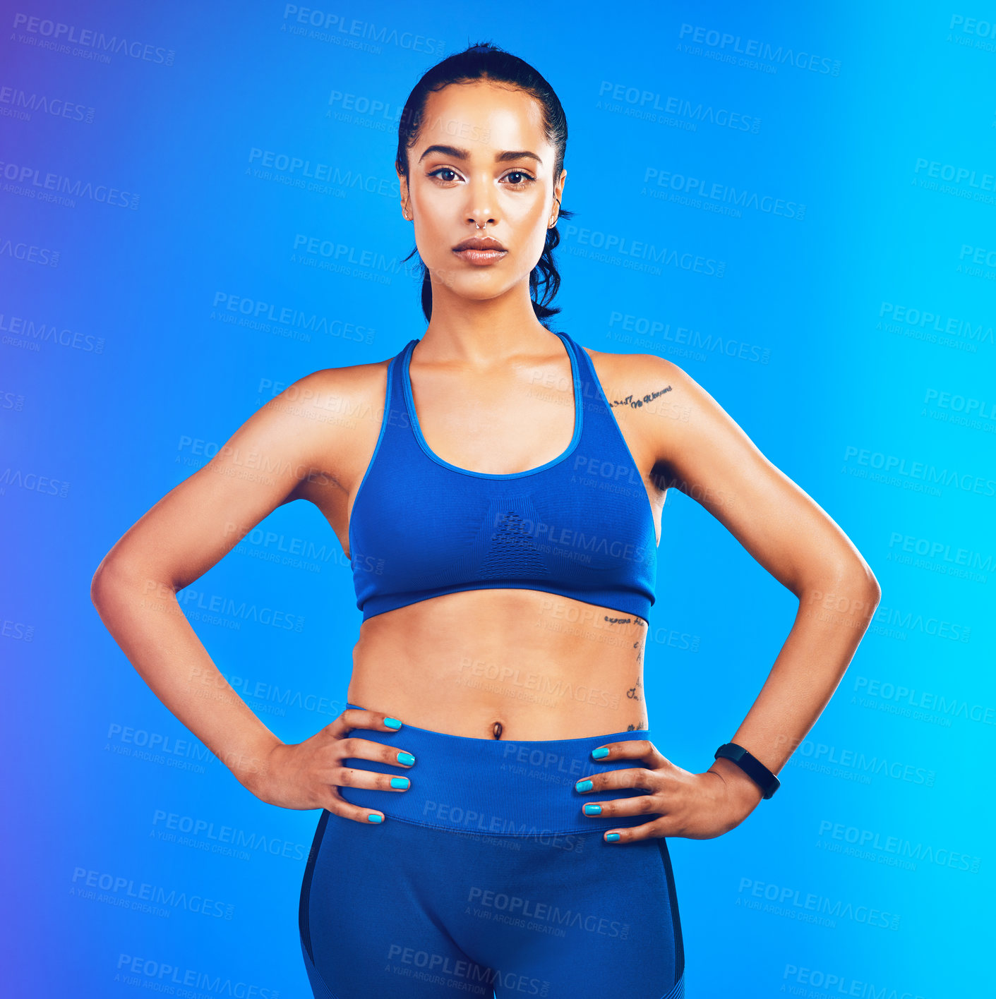 Buy stock photo Studio portrait of an attractive young sportswoman posing with her hands on her hips against a blue background