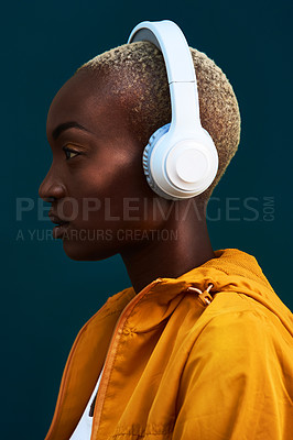 Buy stock photo Cropped shot of an attractive young sportswoman standing alone against a dark background and listening to music through headphones