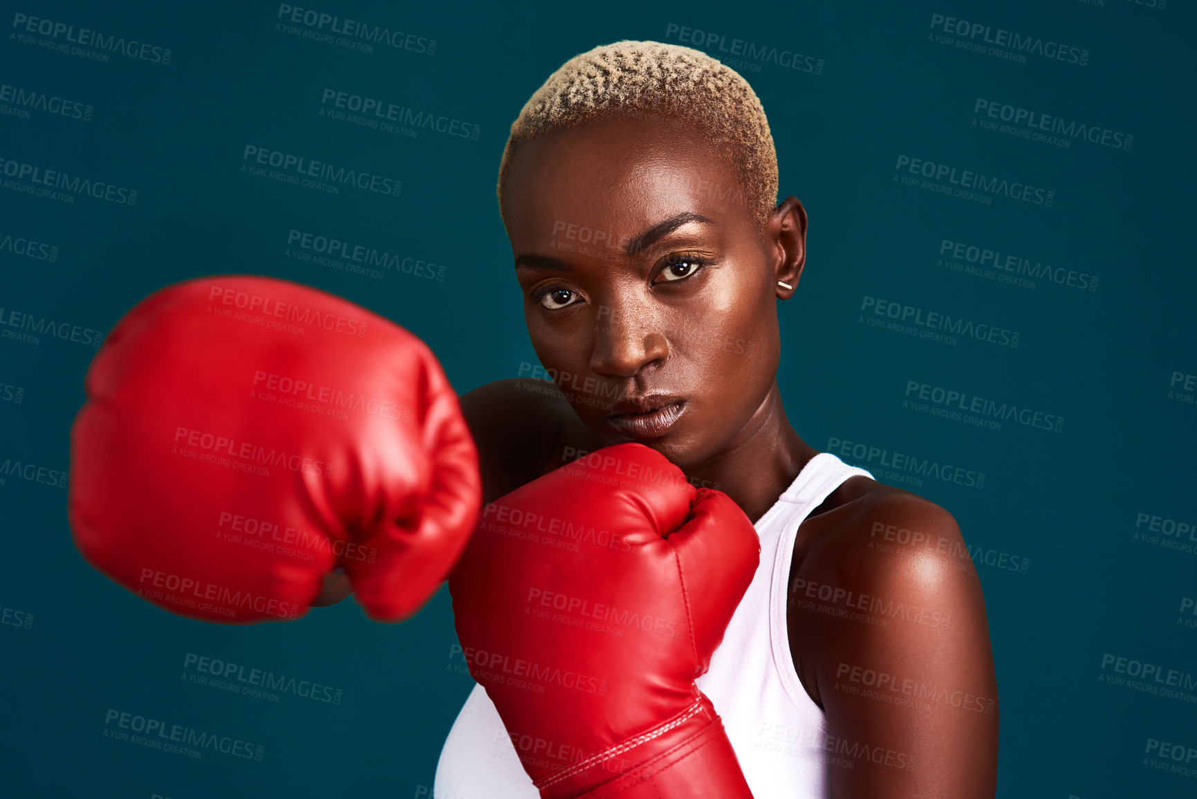Buy stock photo Cropped portrait of an attractive young female boxer working out against a dark background in the studio
