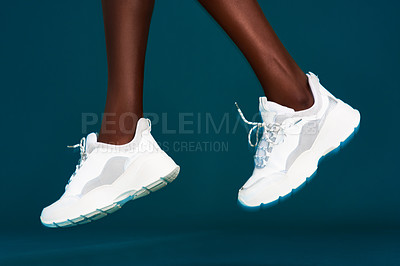 Buy stock photo Cropped shot of an unrecognizable sportswoman wearing her sneakers before working out against a dark background in the studio