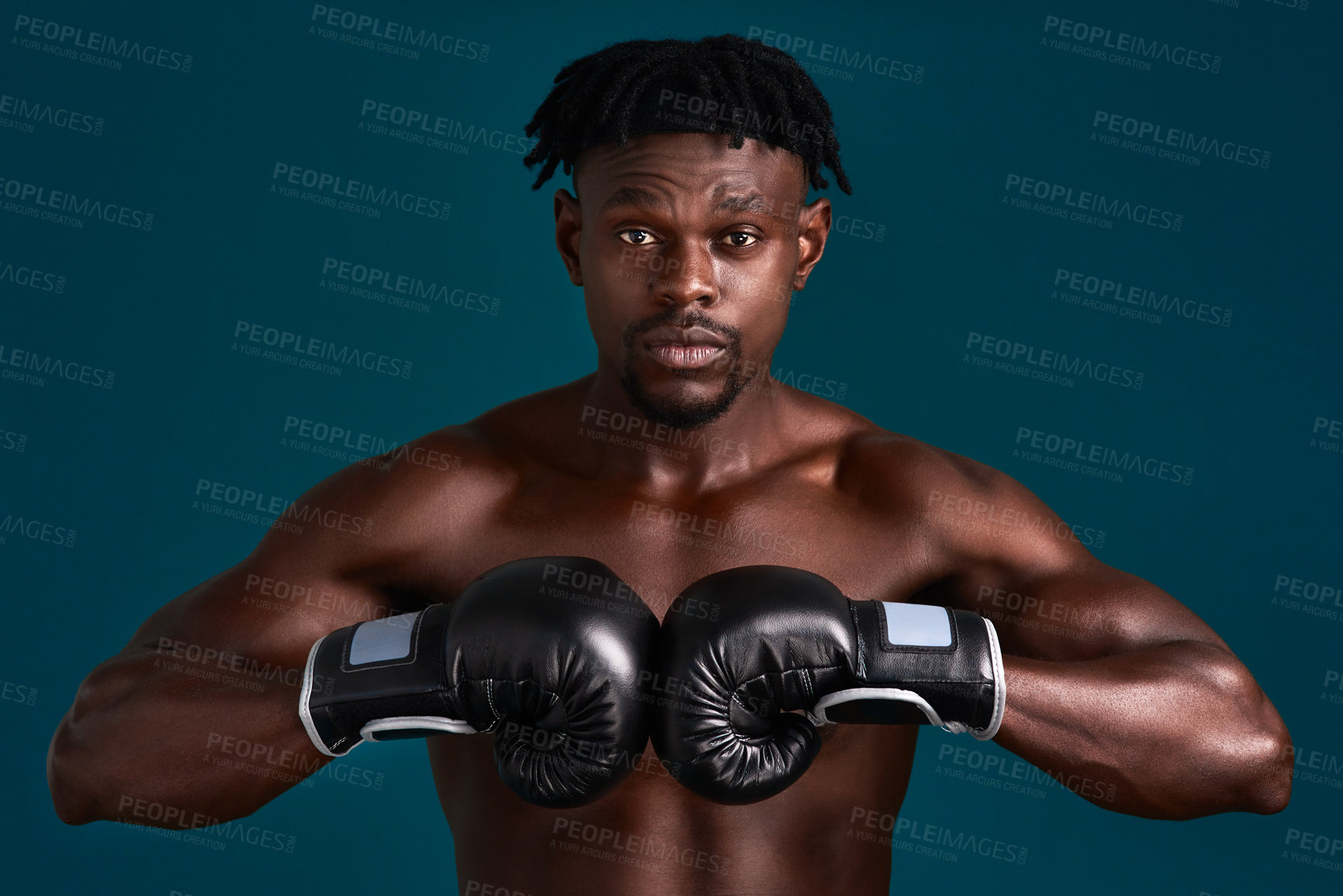 Buy stock photo Cropped portrait of a handsome young boxer working out against a dark background in the studio