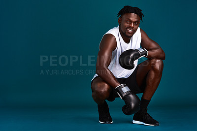 Buy stock photo Full length portrait of a handsome young boxer crouching against a dark background with his boxing gloves on