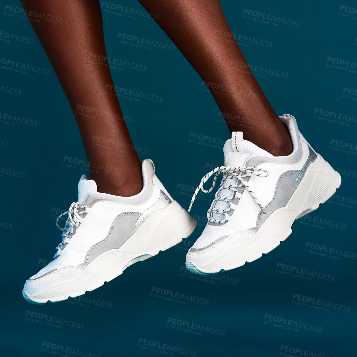 Buy stock photo Cropped shot of an unrecognizable sportswoman wearing her sneakers before working out against a dark background in the studio