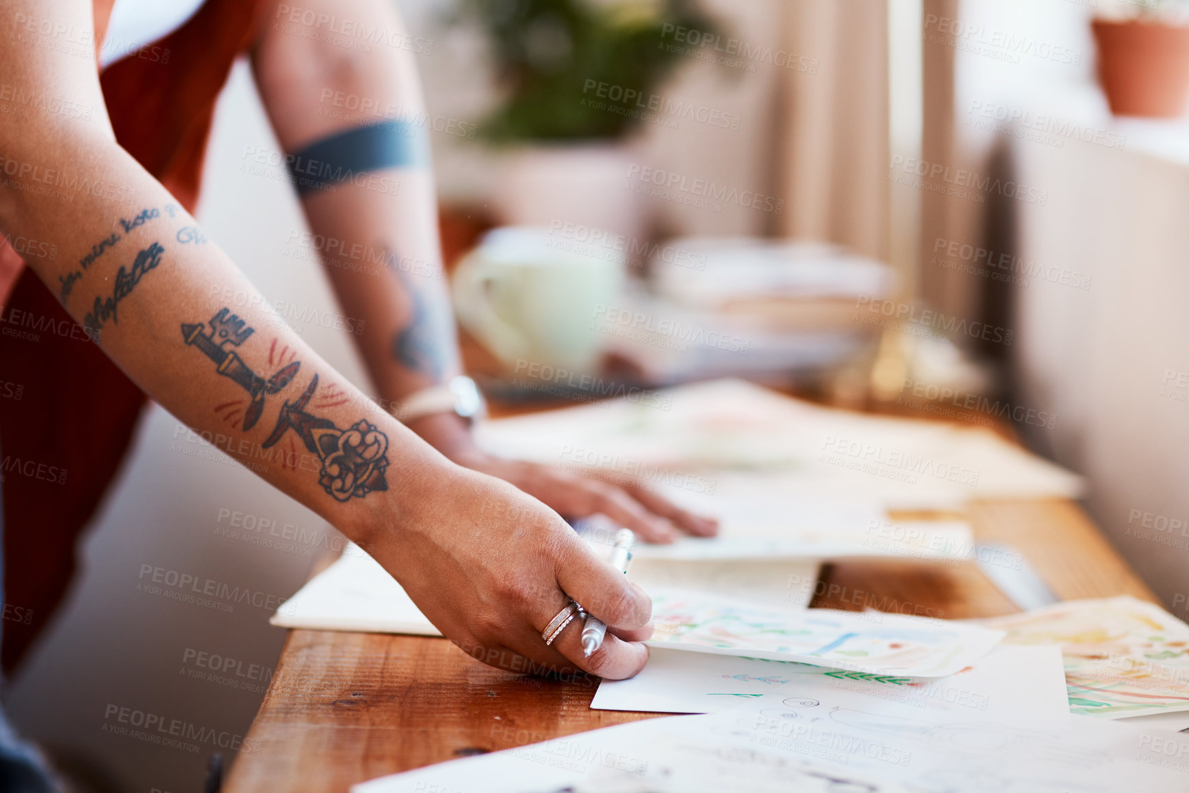Buy stock photo Cropped shot of an unrecognizable woman looking at her sketches on a table at home