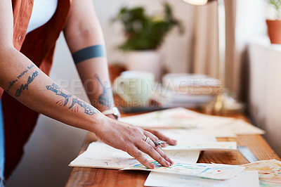Buy stock photo Cropped shot of an unrecognizable woman looking at her sketches on a table at home
