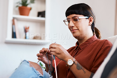Buy stock photo Cropped shot of a young woman knitting while relaxing at home