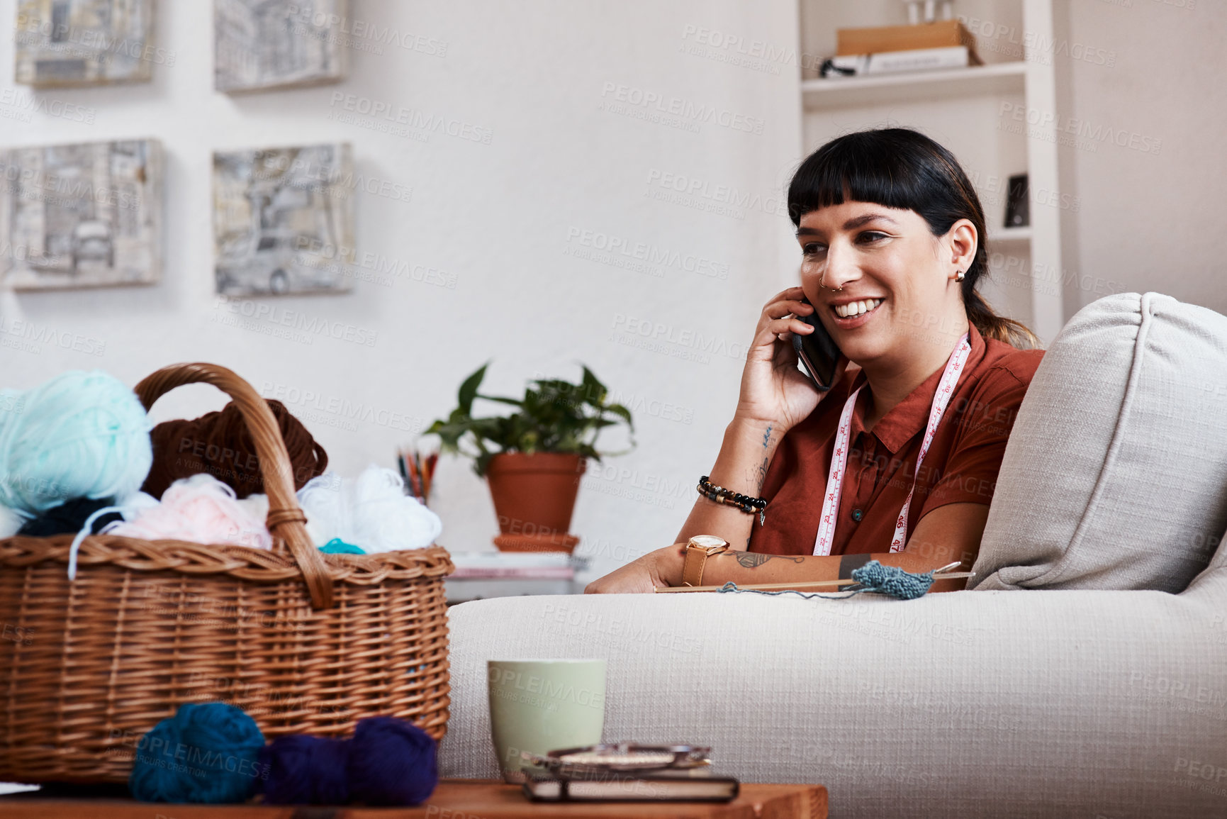 Buy stock photo Shot of a clothing designer talking on her phone while relaxing at home