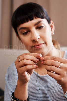 Buy stock photo Cropped shot of a young woman trying to put thread through an eyelet