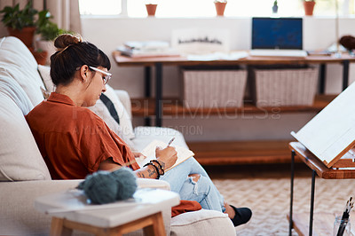 Buy stock photo Shot of an attractive young woman drawing while relaxing on the sofa at home