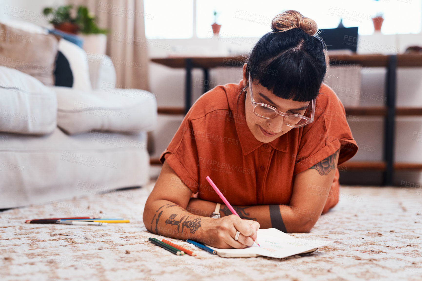 Buy stock photo Shot of a young woman using coloring pens while drawing at home