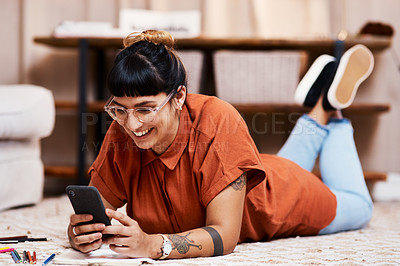 Buy stock photo Shot of a young woman using her cellphone while drawing at home