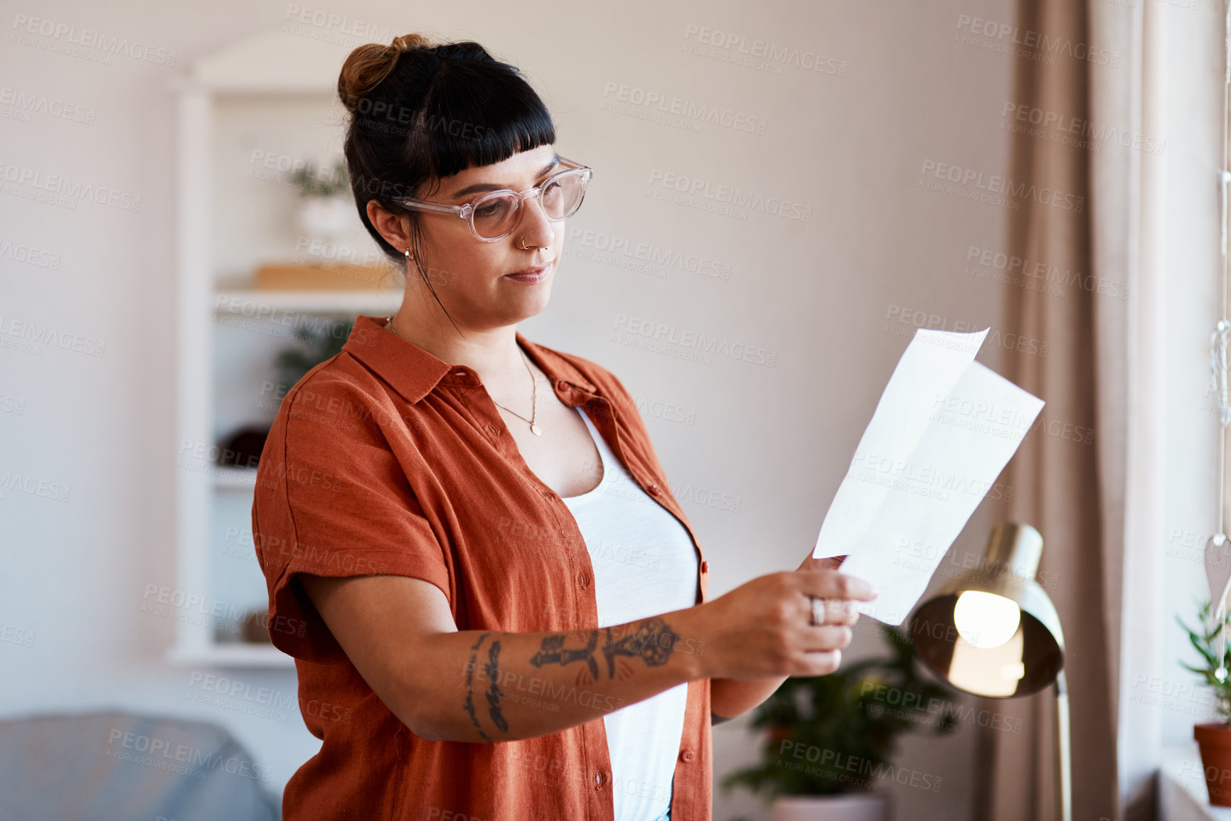 Buy stock photo Cropped shot of a young woman looking at paperwork at home